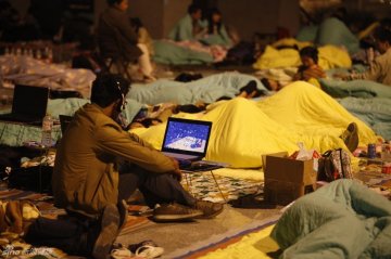 14.师生在教学楼打地铺，一位学生在看篮球