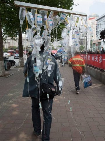 男子扛输液瓶游街抗议滥用抗生素