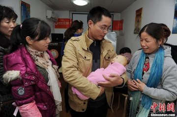 李大斌（图中）正在学习抱婴儿