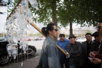 男子扛输液瓶游街抗议滥用抗生素