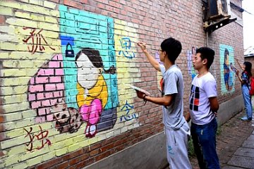 大学生绘墙画呼吁关注留守儿童