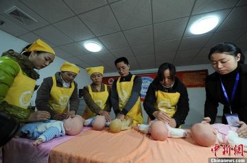 李大斌（图左四）与多名女学员一起接受婴儿抚触培训